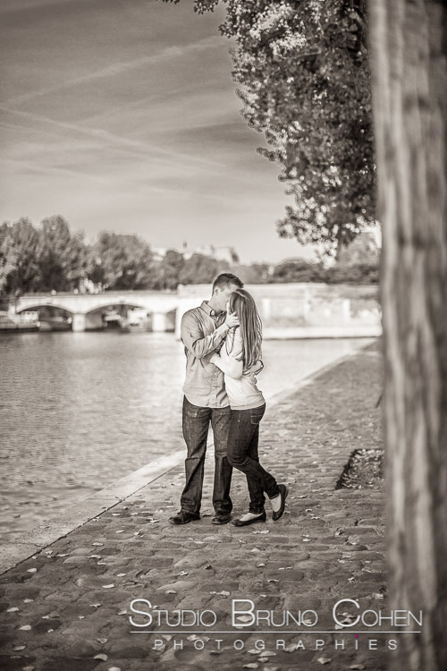 portrait kissing couple stand in paris from quai de seine black and white