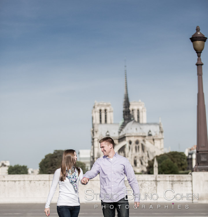 portrait jumping couple hand in hand front of notre dame cathedral in paris engagement session at sunrise