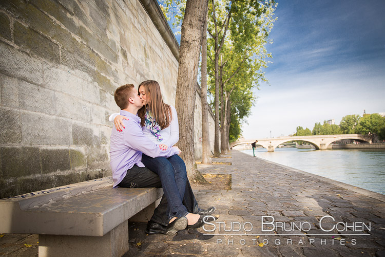 portrait kissing couple from quai de seine in paris blue sky at sunrise