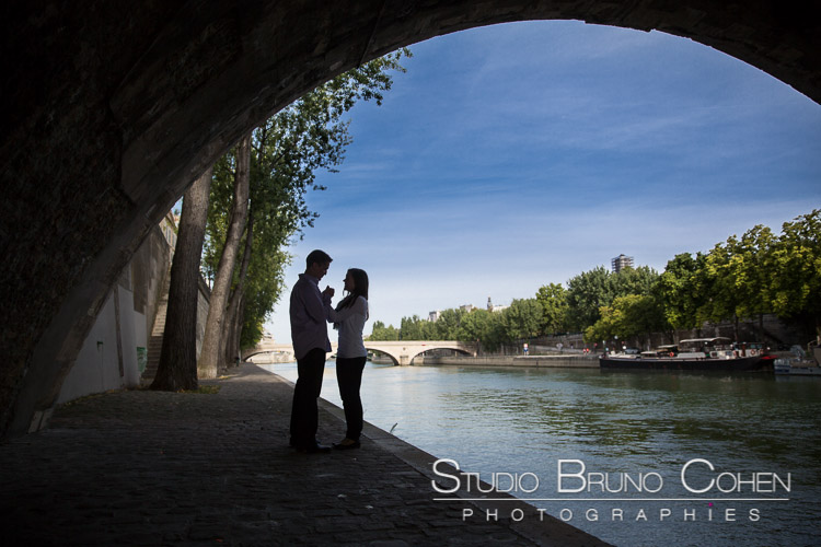 portrait couple in love from quai de seine in paris proposal engagement session at sunrise blue sky love
