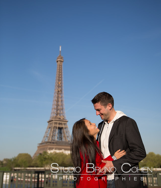 portrait couple look at each other in love front Eiffel Tower blue sky happy kiss smile