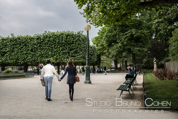 proposal in paris portrait couple hand in hand walk on park near notre dame cathedral