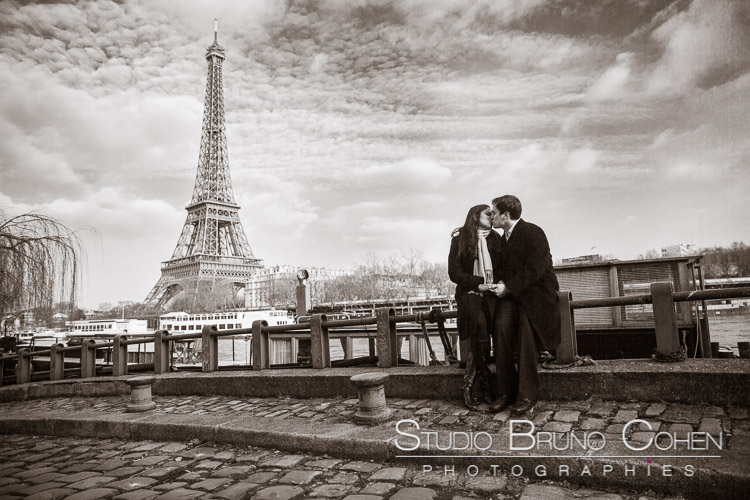 portrait couple standing in bridge in love kiss front of Eiffel Tower black and white 