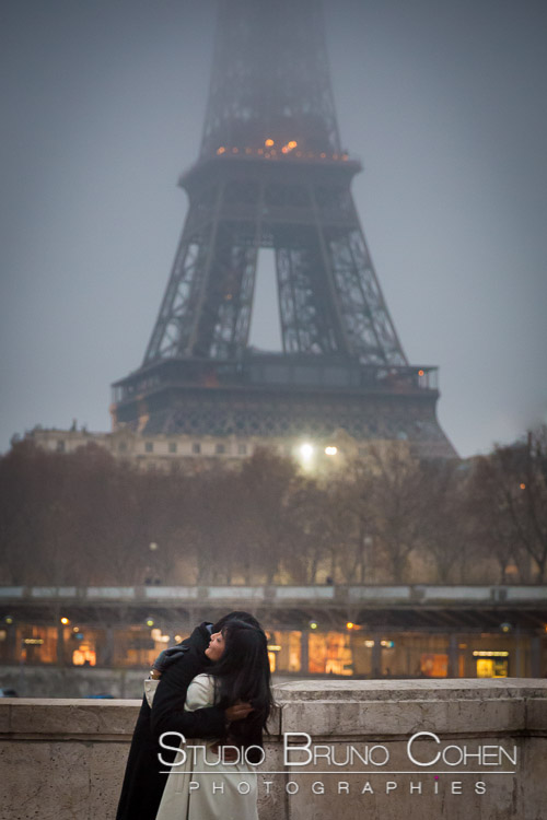 portrait couple hugging in love front of Eiffel Tower in paris at night winter emotions engagement session