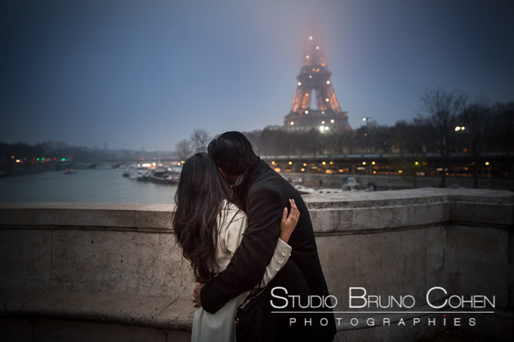 portrait hugging couple in love look Eiffel Tower at night winter engagement session 