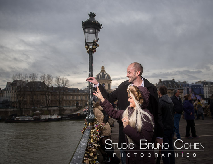 portrait couple in love throw lock key Valentine's Day from lock bridge in paris at winter