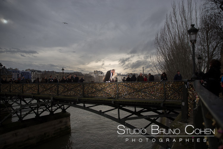 portrait kissing couple from lock bridge in paris at winter sunset 