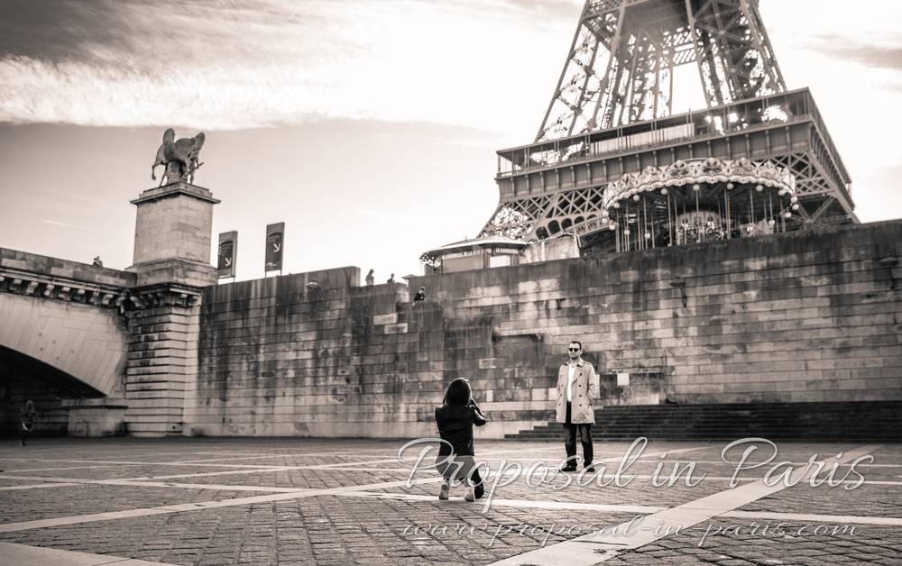 couple take picture front of eiffel tower black and white proposal in paris