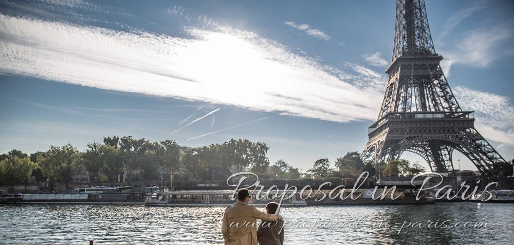 couple in love from quai de seine front of eiffel tower proposal in paris blue sky