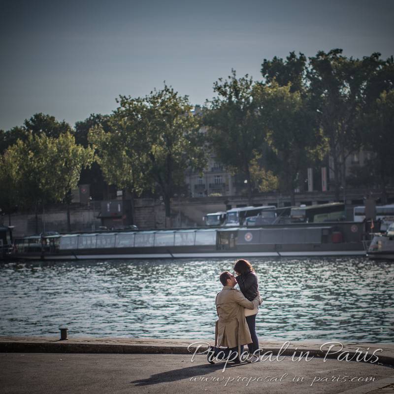 surprise proposal in paris from quai de seine front of eiffel tower kissing couple