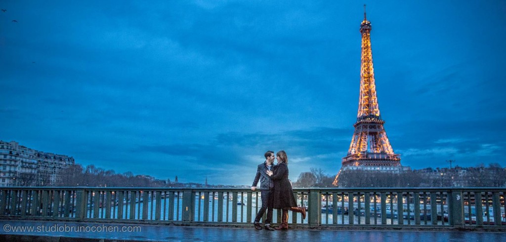 portrait couple in love face to face from bir hakeim bridge front of Eiffel Tower at night winter proposal in paris 