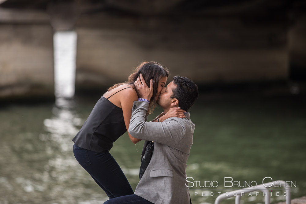 surprise proposal in paris front of eiffel tower on quai de seine kissing couple 