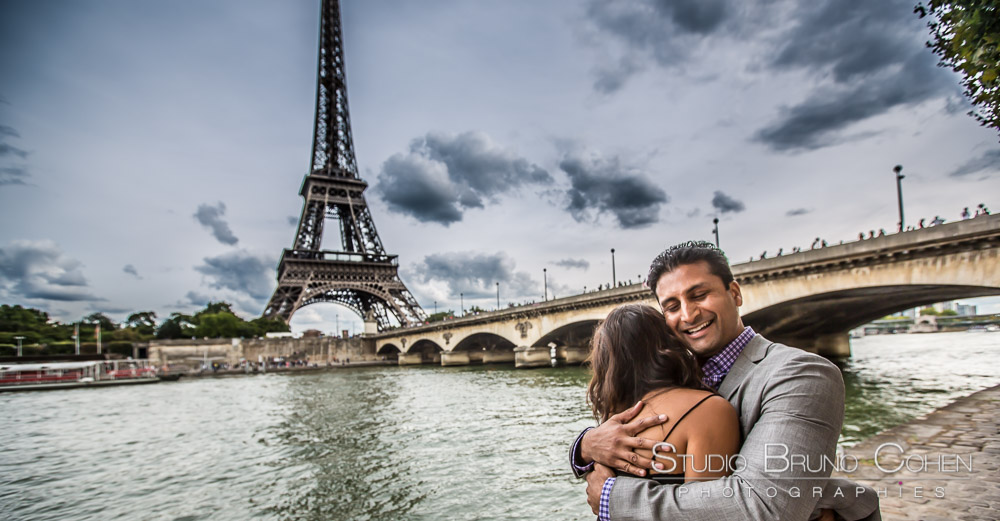 couple hugs in paris from quai de seine front of eiffel tower at summer