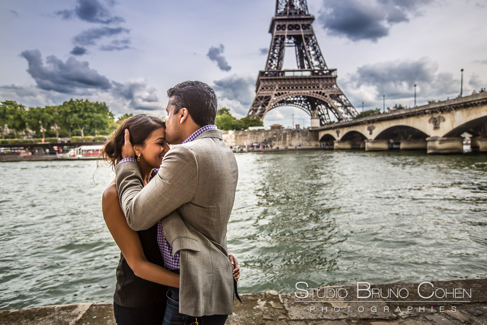couple kiss on forehead surprise proposal in parisfrom quai de seine front of eiffel tower
