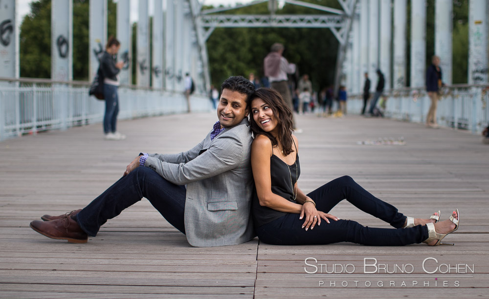 couple back to back in love from paris on bebilly walkway front of eiffel tower at summer blue sky smile