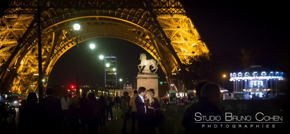 kisisng couple at night in paris front of eiffle tower 