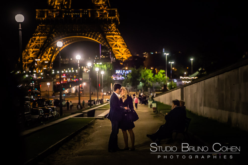 couple hugs in love in paris front of eiffel tower at night