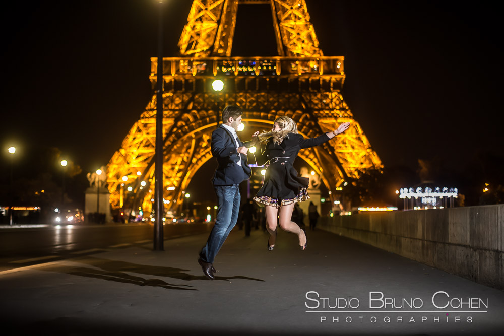 jumping couple at night in paris front of eiffel tower love