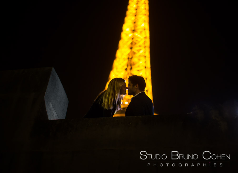 kissing couple at night in paris front of eiffel tower 