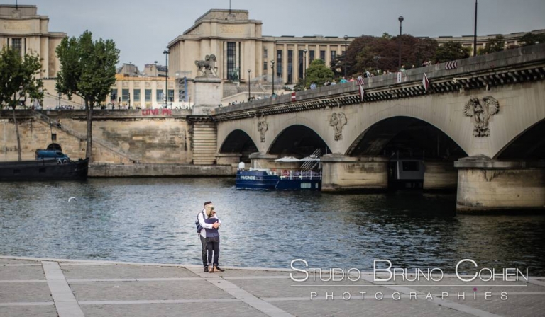 couple stand on quai de seine near eiffel tower in paris