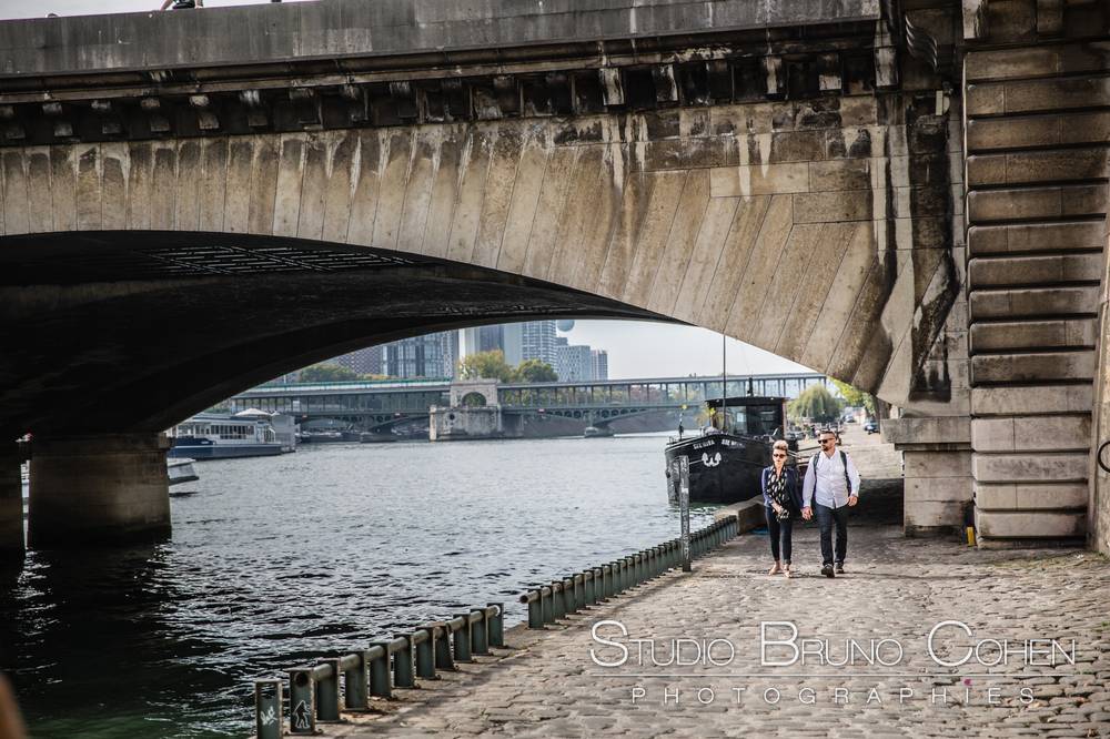 couple walk on quai de seine near eiffel tower from paris