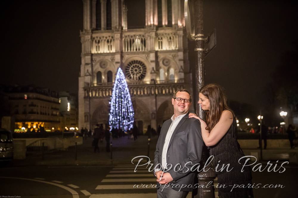 couple in their 30's smiling at each other in front of Notre-Dame de Paris
