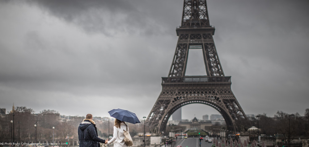 couple hand in hand in trocadero square front of Eiffel Tower under the rain proposal in Paris at winter
