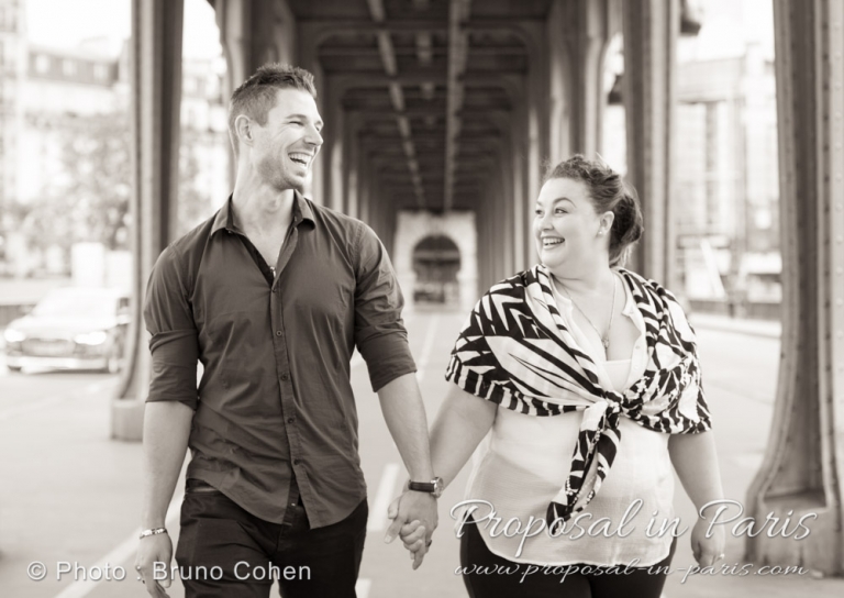 candid couple in love walking under Bir Hakeim bridge near Eiffel Tower in Paris black and white 