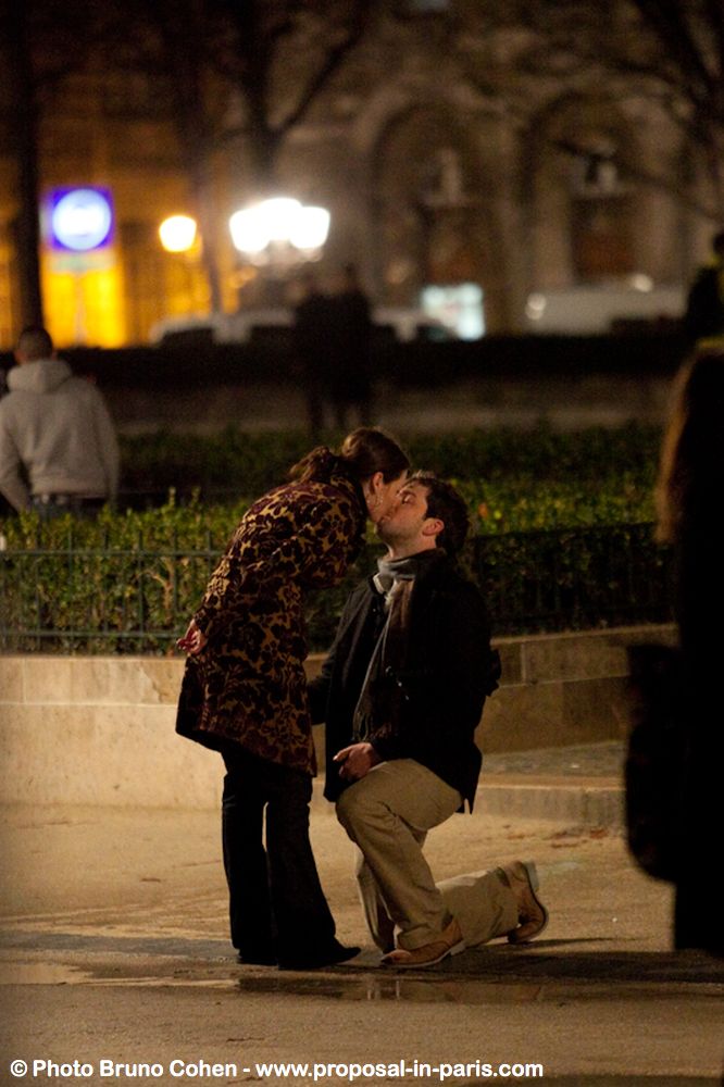 surprise proposal in paris couple in love kiss notre dame cathedral at night