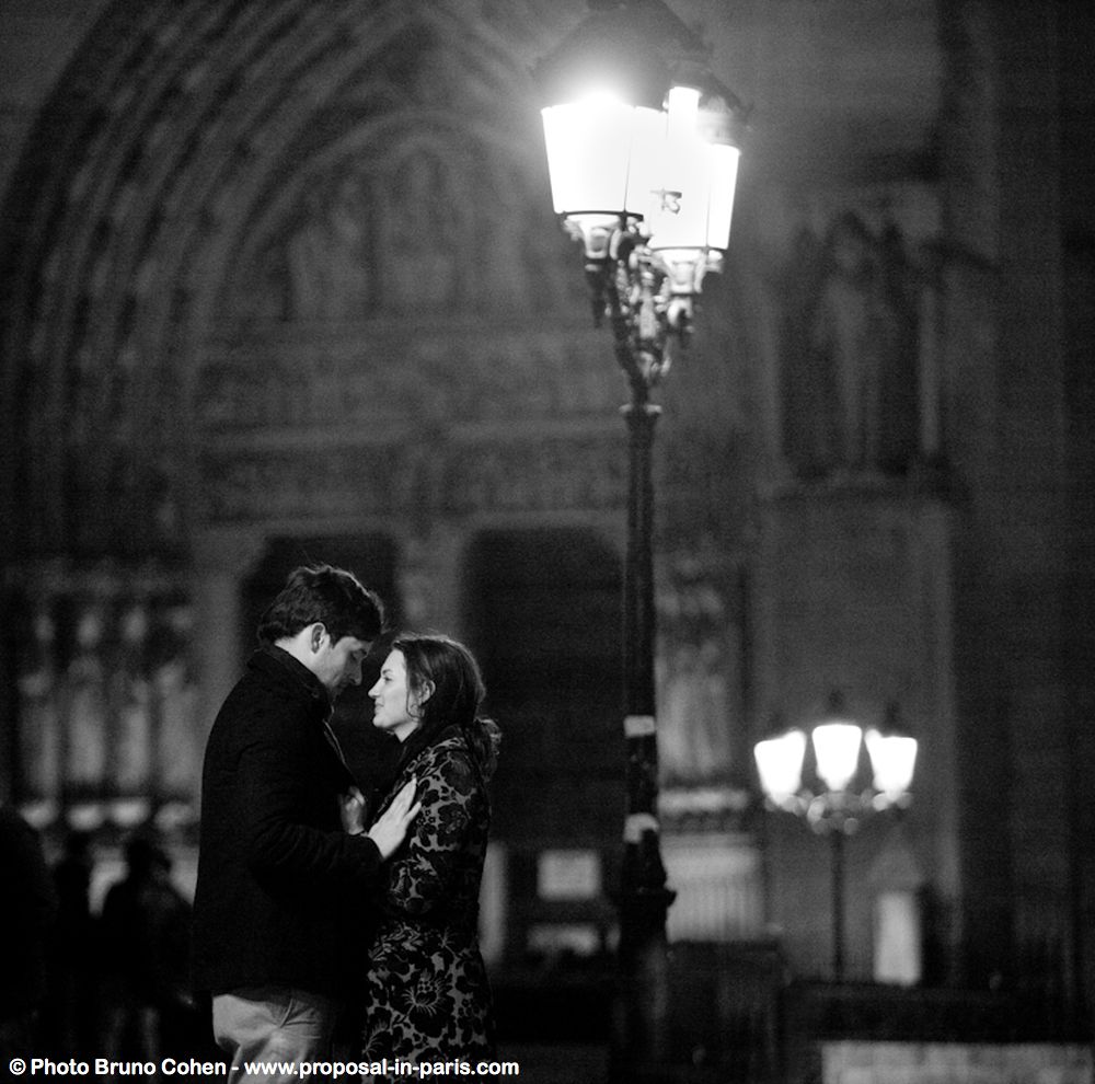 portrait couple in love from notre dame cathedral proposal surprise at night