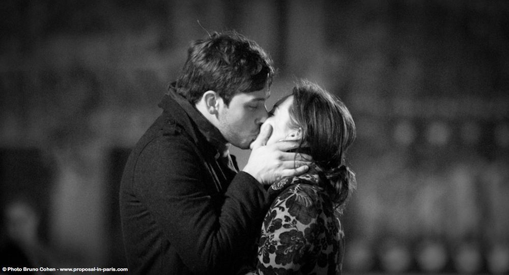 portrait kissing couple from notre dame cathedral in paris surprise proposal emotion black and white