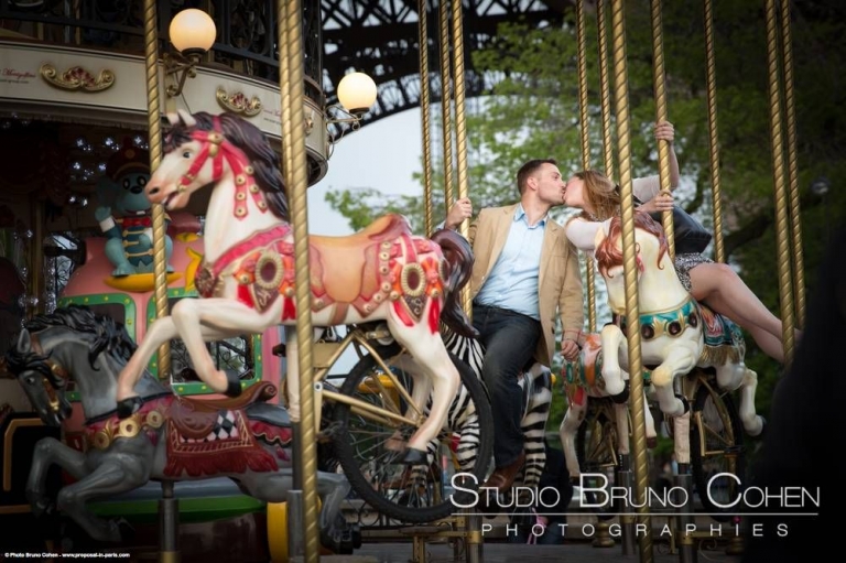 portrait kissing couple ride on horses from carousel Eiffel Tower love engagement proposal 