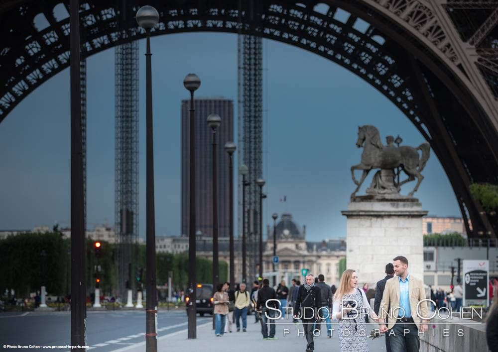 portrait couple hand in hand walking front of Eiffel Tower in paris proposal at sunset