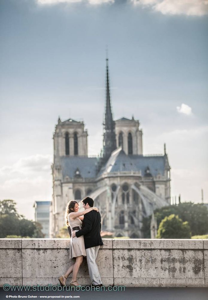 portrait couple standing hugs face to face in love from paris front of notre dame cathedral 
