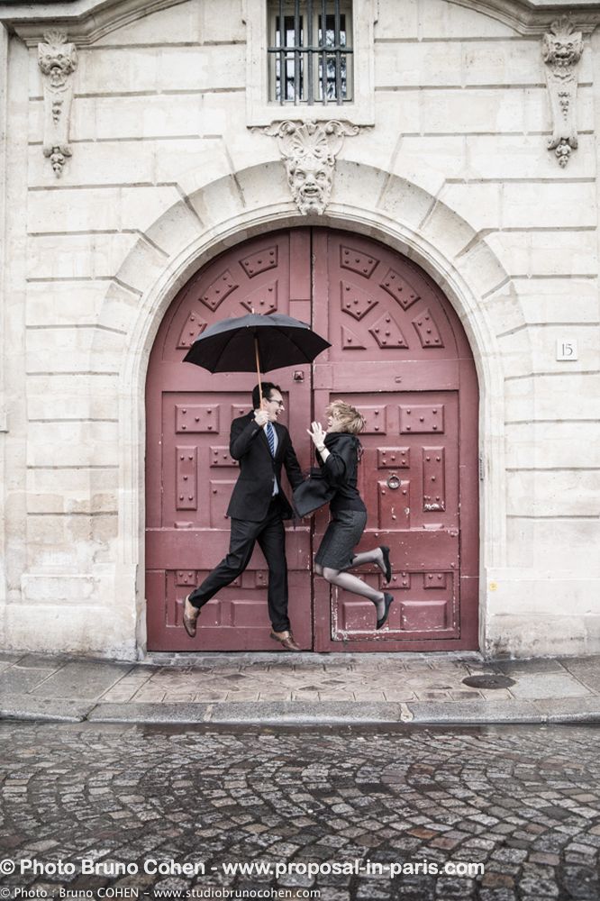 portrait jumping couple in paris proposal umbrella