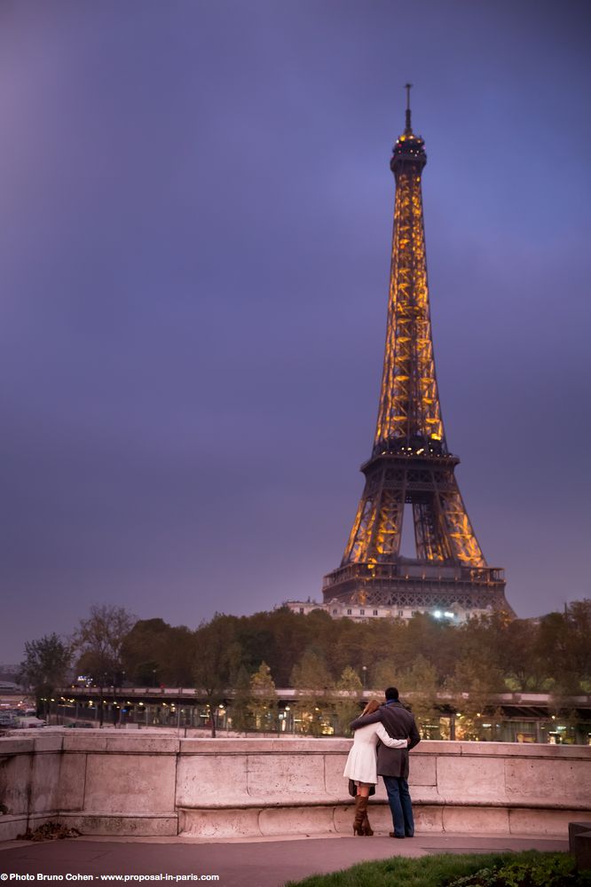 portrait hugging couple in love front of Eiffel Tower at sunset winter