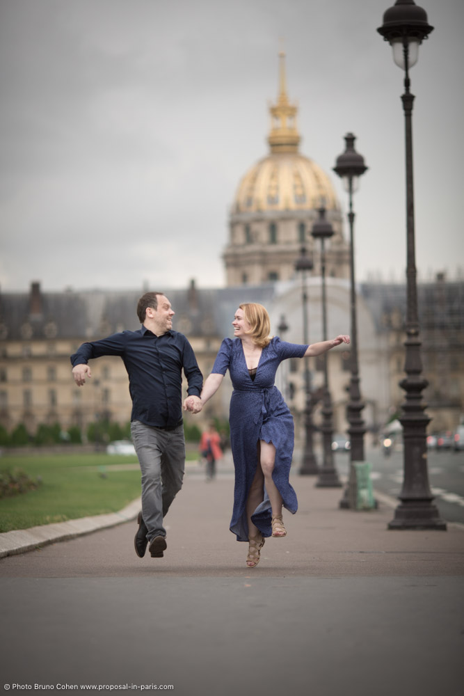 couple jumping smile proposal in paris invalides cloudy