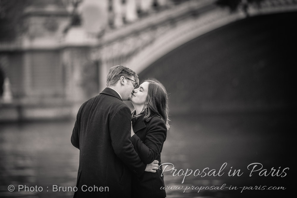 kissing couple behind bridge black and white in paris