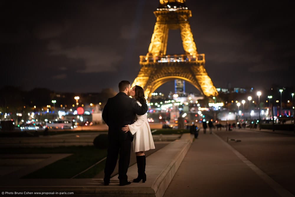 kissing couple in front of Eiffel Tower by night