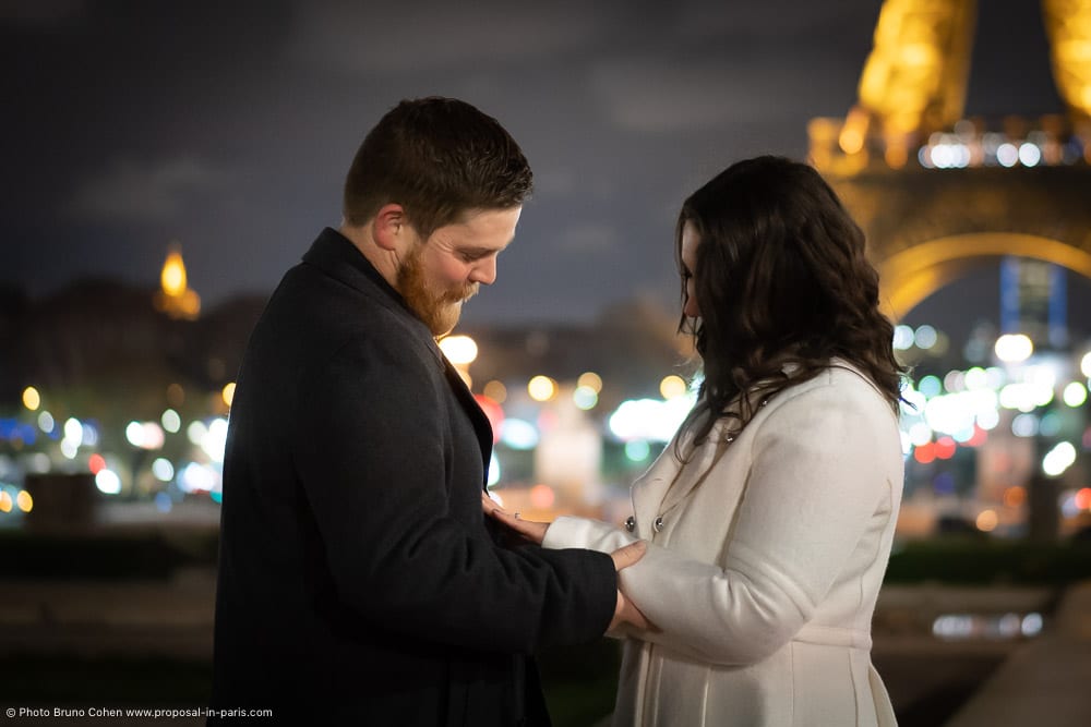 after proposal couple look the ring front Eiffel Tower at night
