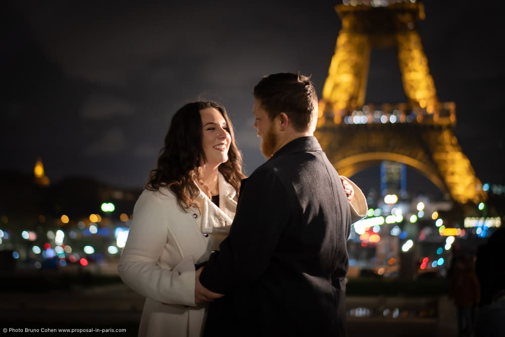 couple in love look at each other front of Eiffel Tower at night