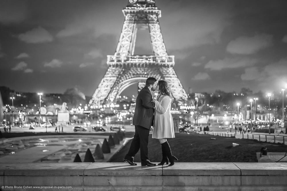 couple kissing front the Eiffel Tower at night in black and white