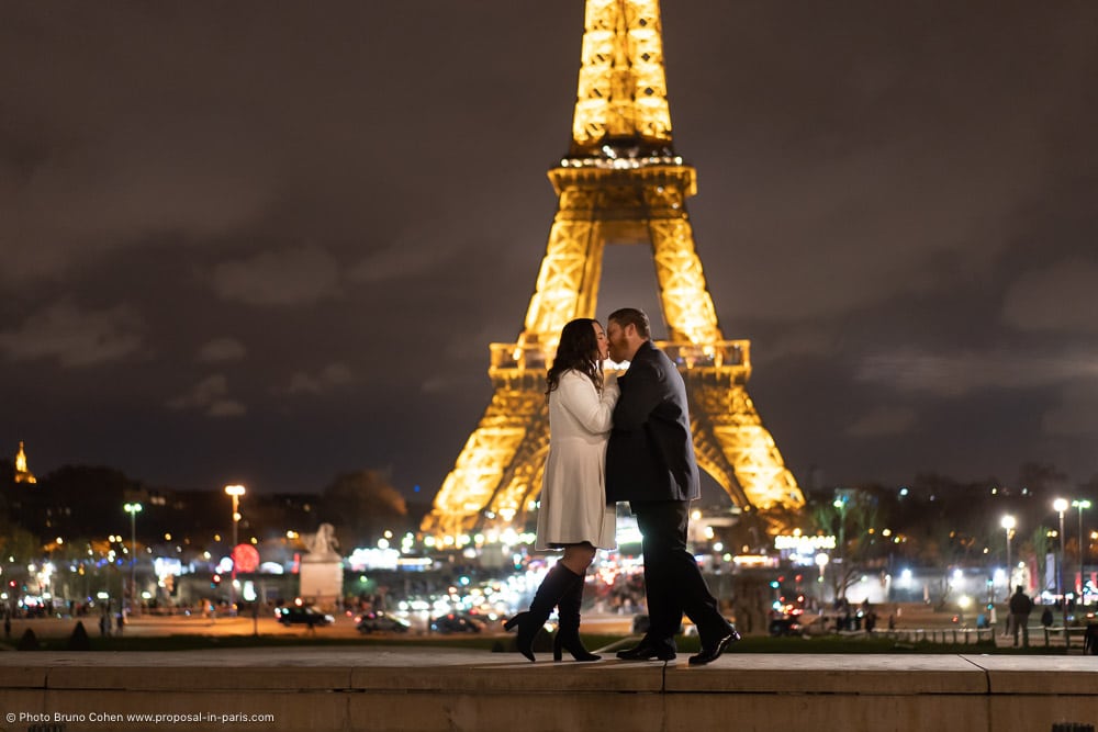 couple kissing front the Eiffel Tower at night