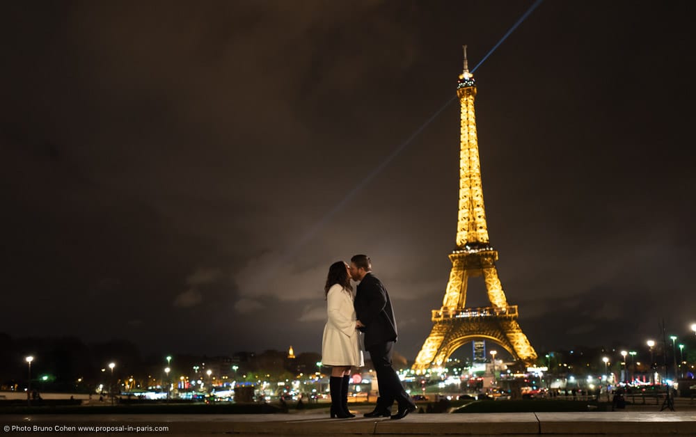 couple hand in hand standing front of Eiffel Tower at night
