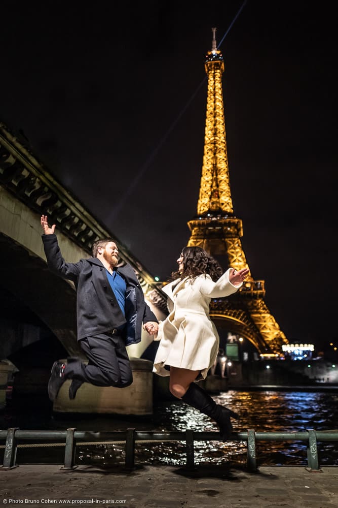 couple jumping front Eiffel Tower at night