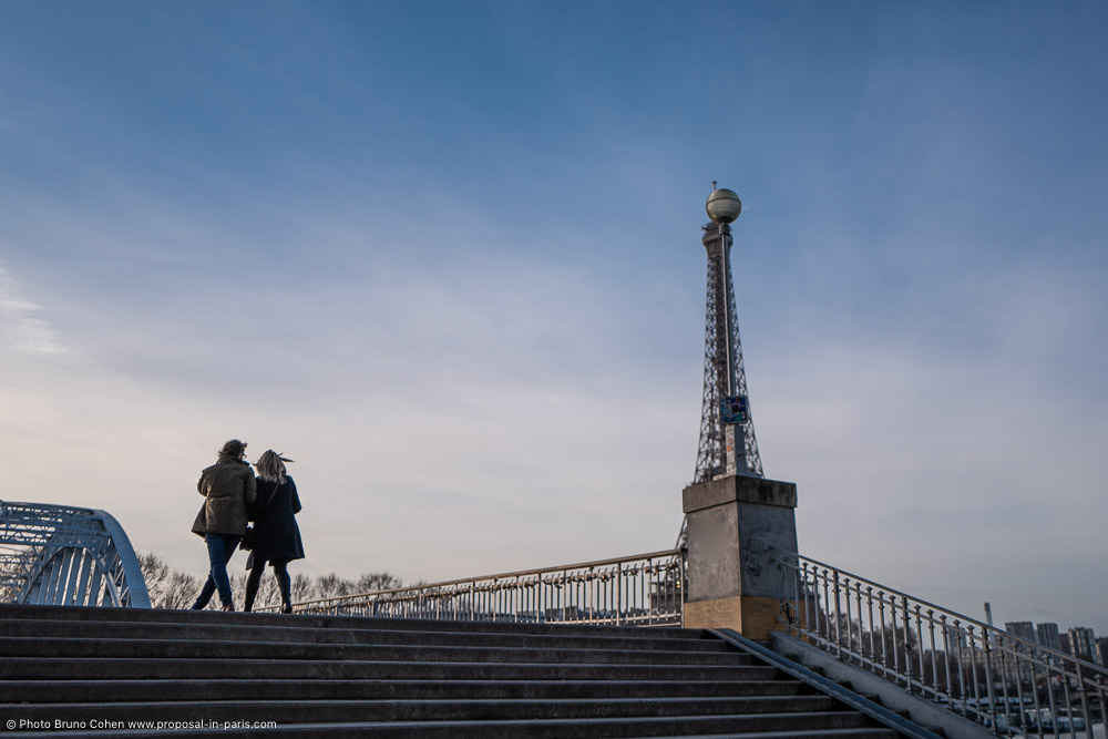 couple walk on a bridge front of Eiffel Tower