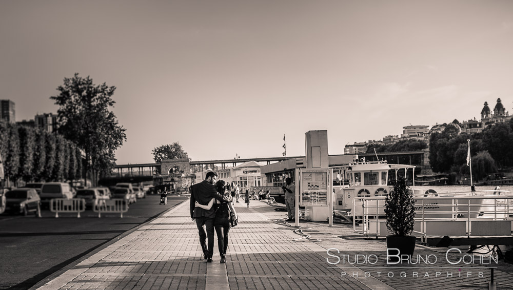 portrait couple in love walk on quai de seine front of bir hakeim bridge proposal in paris kiss black and white