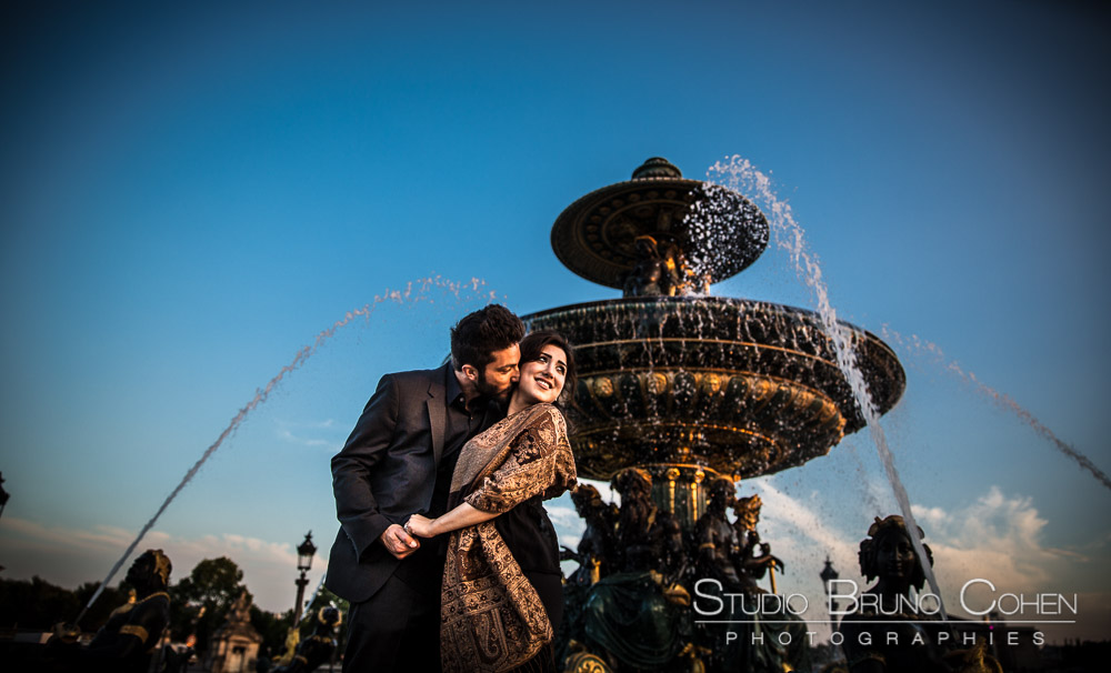 portrait kissing couple in love from paris  fountain at sunset proposal summer blue sky