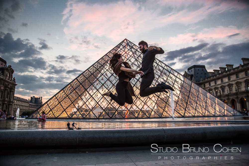 beautiful portrait jumping couple love fromlouvres pyramid and louvres museum at sunset colors summer proposal 