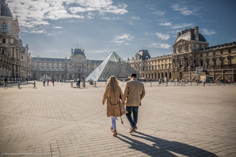 couple hand in hand walking in paris at louvres pyramid